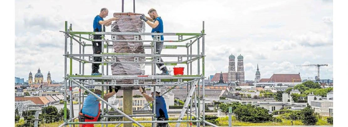 Construction work on scaffolding on an artificial chimney above the roofs in Munich, four men on work matters